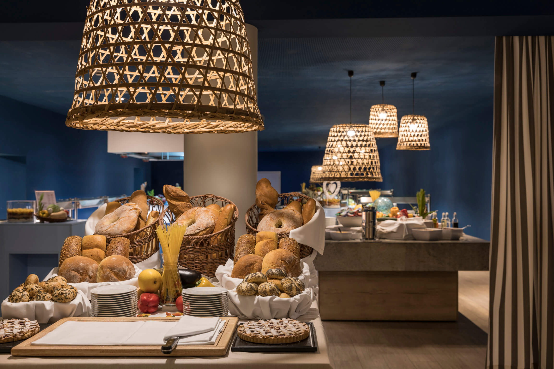 Ein stilvoller Frühstücksbuffetbereich mit frischem Brot, Obst und ansprechender Beleuchtung.
