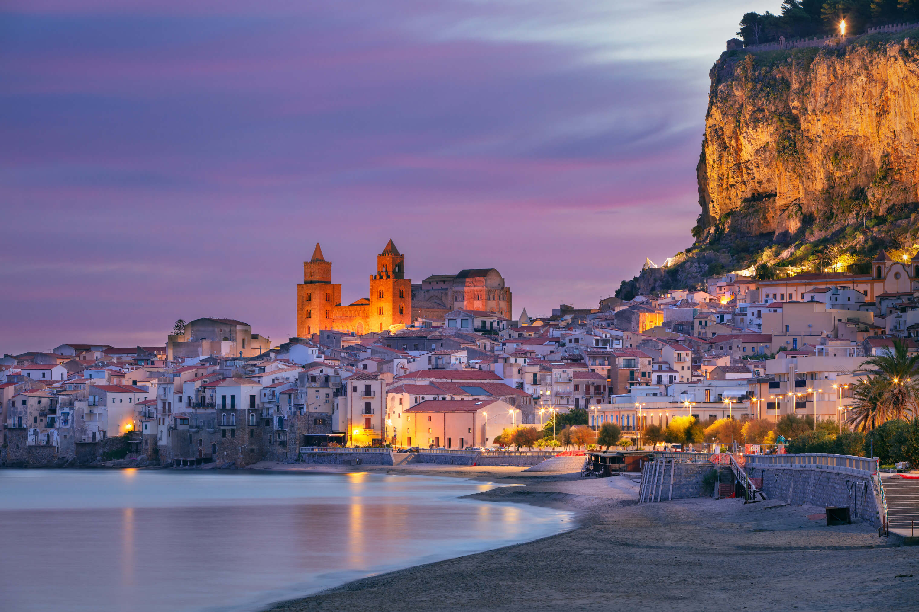 Ein malerisches Küstenstädtchen mit historischen Gebäuden und warmem Abendlicht am Meer.