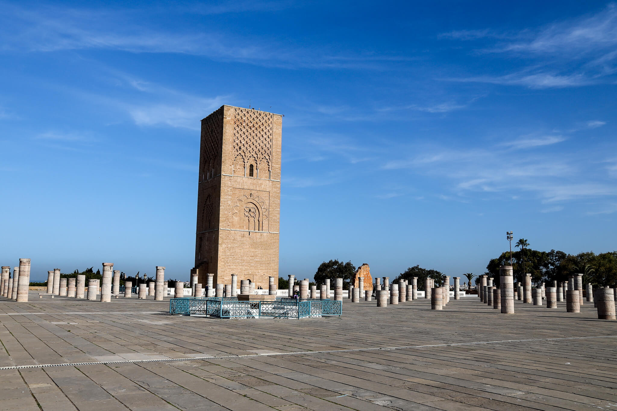 Der Hasek-Turm in Rabat steht majestätisch zwischen Säulenruinen unter blauem Himmel.