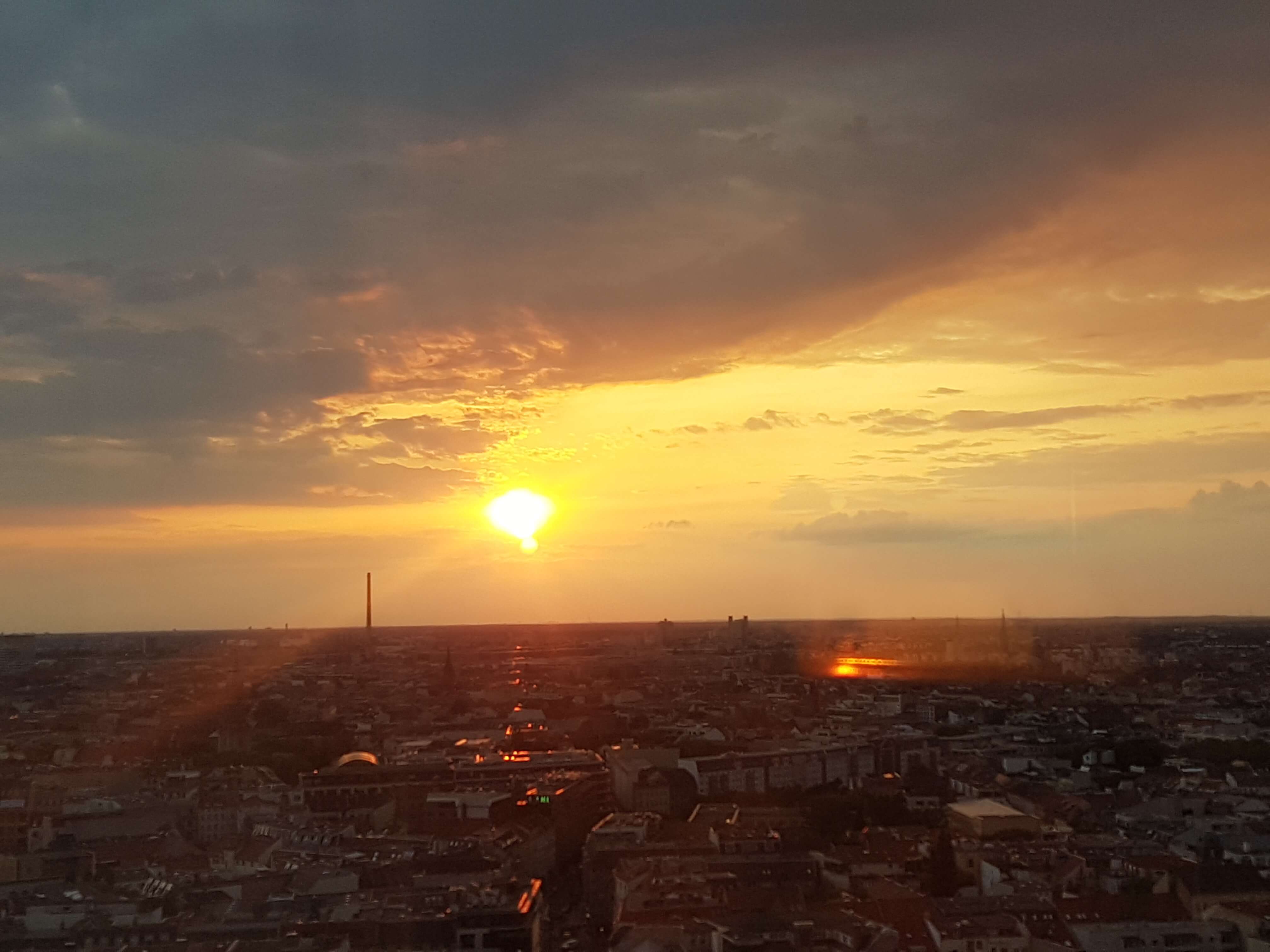 Ein Sonnenuntergang über einer Stadt, mit goldenen und orangefarbenen Himmel und Wolken. Schönheit der Natur.