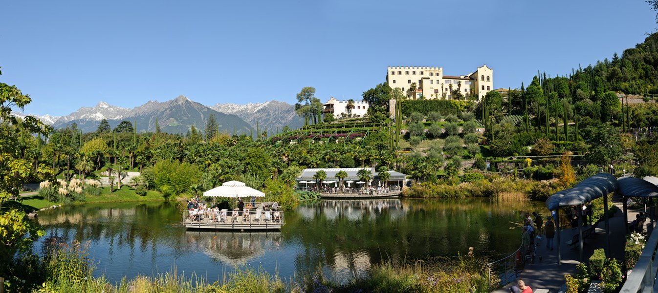 Ein schöner Park mit einem Teich, umgeben von Bergen und üppiger Vegetation, ideal für Entspannung und Genuss.