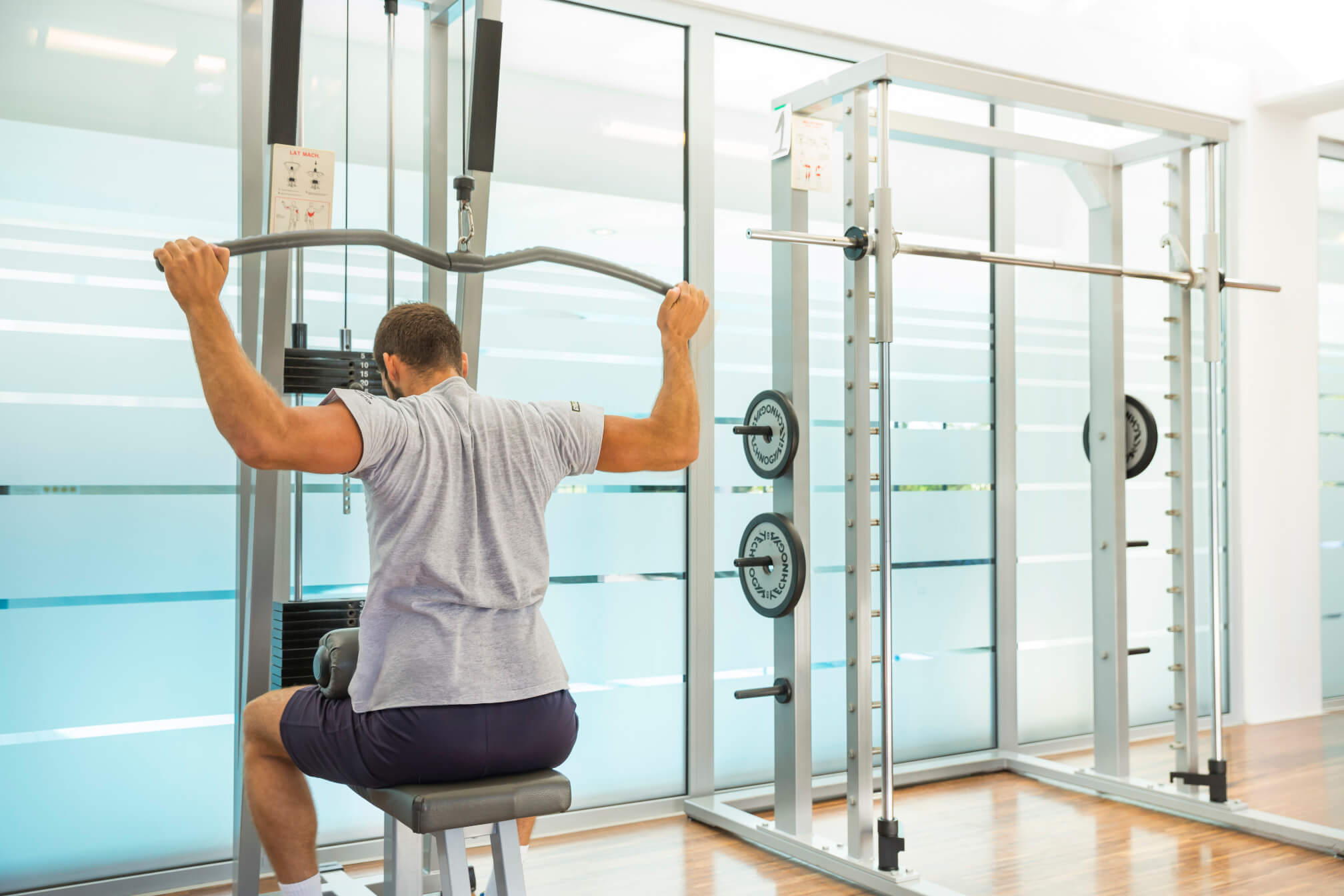 Ein Mann trainiert an einem Geräte-Rudermaschine im modernen Fitnessstudio. Helle Atmosphäre und viel Licht.