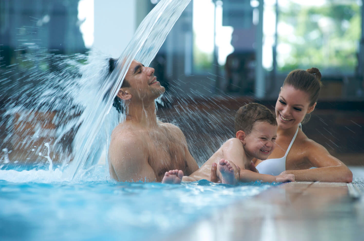 Eine Familie hat Spaß im Pool, spritzendes Wasser, Lachen und Freude beim Spielen zusammen.