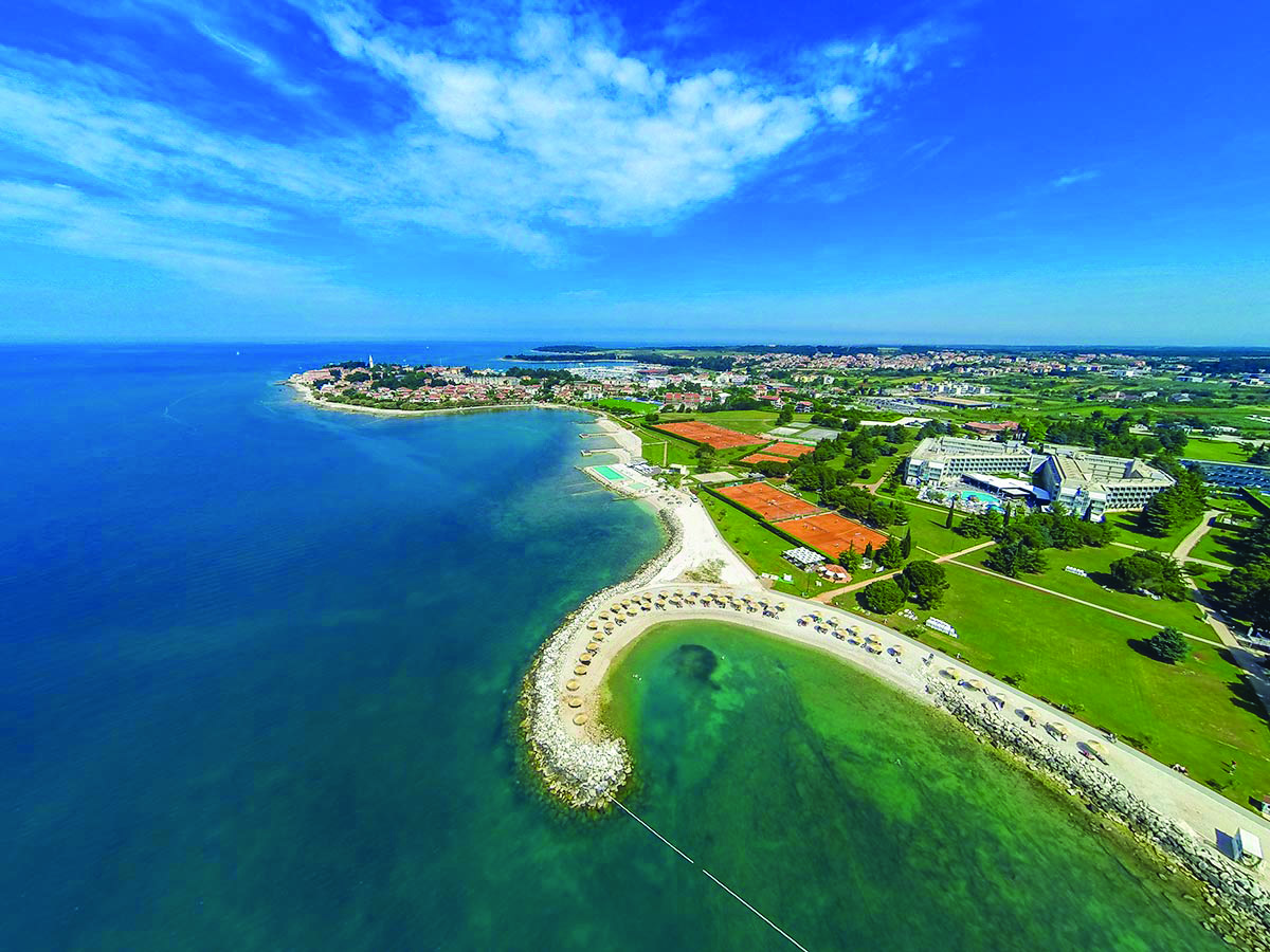 Eine Luftaufnahme zeigt eine wunderschöne Küstenlandschaft mit blauem Wasser, Stränden und grünen Flächen.