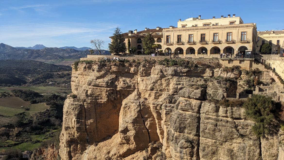 Eine beeindruckende Klippe mit einem charmanten Gebäude und einer weitläufigen Landschaft im Hintergrund.