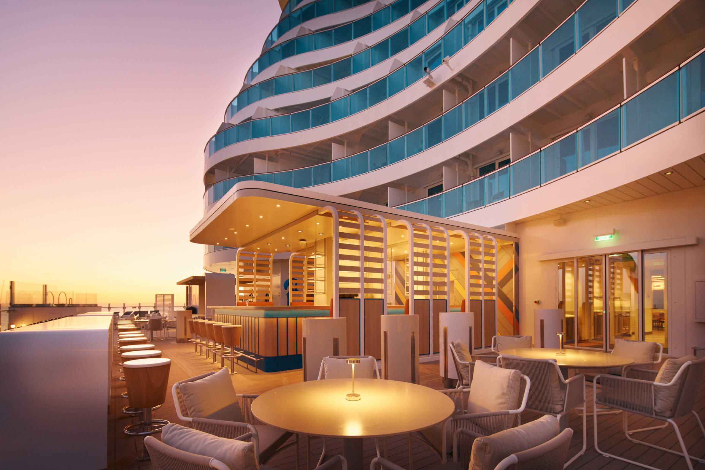 Eine moderne Terrasse mit einer Bar und gemütlichen Sitzbereichen, beleuchtet im warmen Licht der Dämmerung.