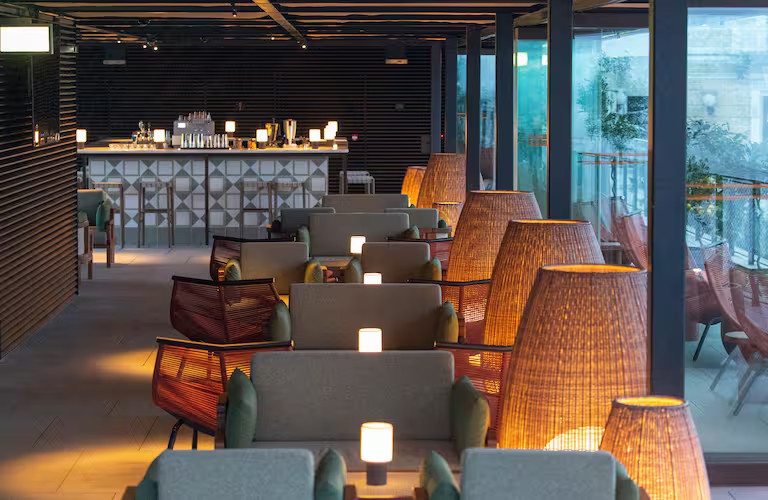 Modernes Café mit eleganten Möbeln, sanfter Beleuchtung und Blick auf die Bar im Hintergrund. Entspanntes Ambiente.