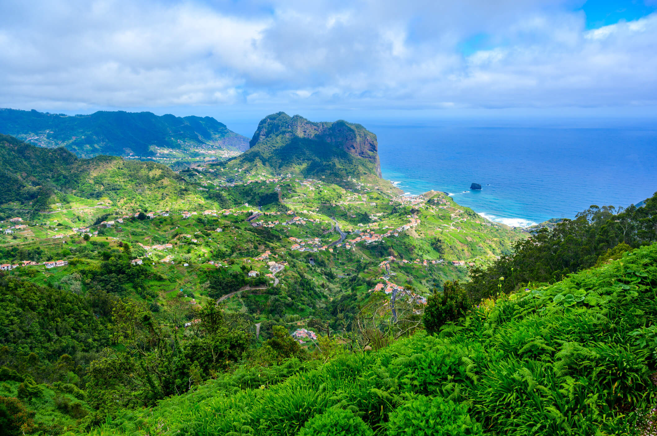 Eine panoramische Landschaft mit grünen Hügeln, einem Felsen und dem blauen Ozean im Hintergrund. Ideal für Naturfreunde.