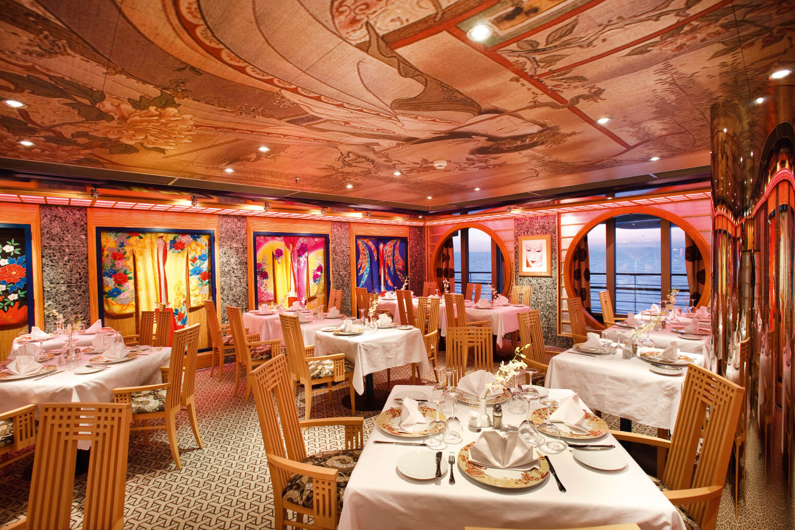 Elegantes Restaurant mit stilvollen Tischen, bunten Gemälden und Meerblick, perfekt für besondere Anlässe.