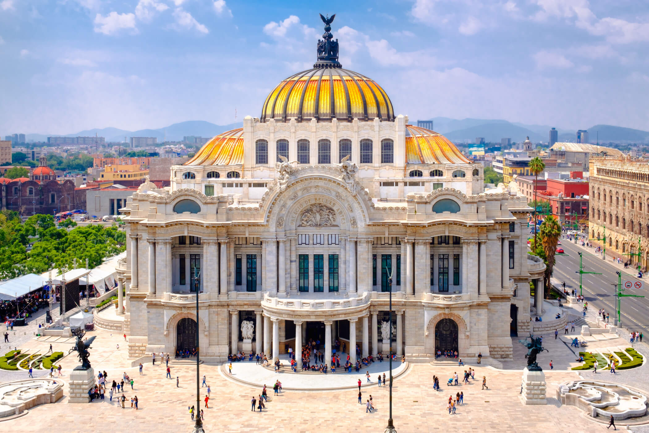 Das Bild zeigt das beeindruckende Palacio de Bellas Artes in Mexiko-Stadt mit seiner goldenen Kuppel und lebhaften Umgebung.