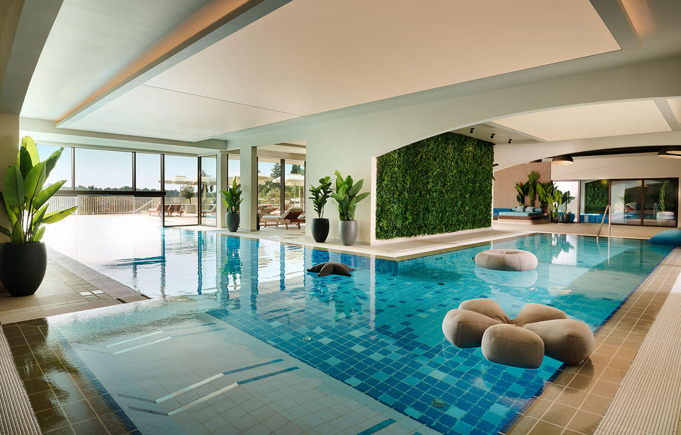 Ein eleganter Innenpool mit Pflanzen, großen Fenstern und modernem Design. Entspannung pur in stilvollem Ambiente.