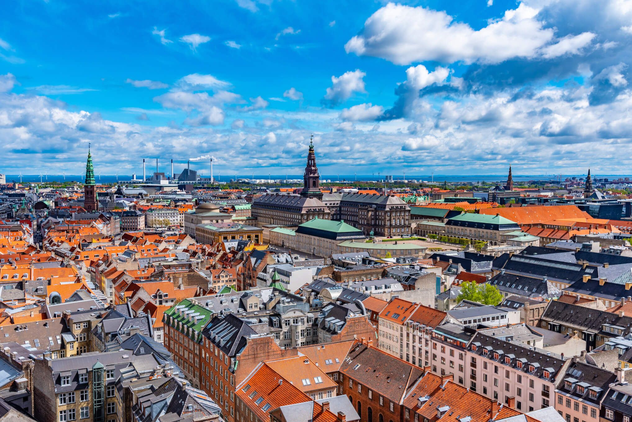 Blick auf die Dächer von Kopenhagen, mit historischen Gebäuden und einem strahlend blauen Himmel.