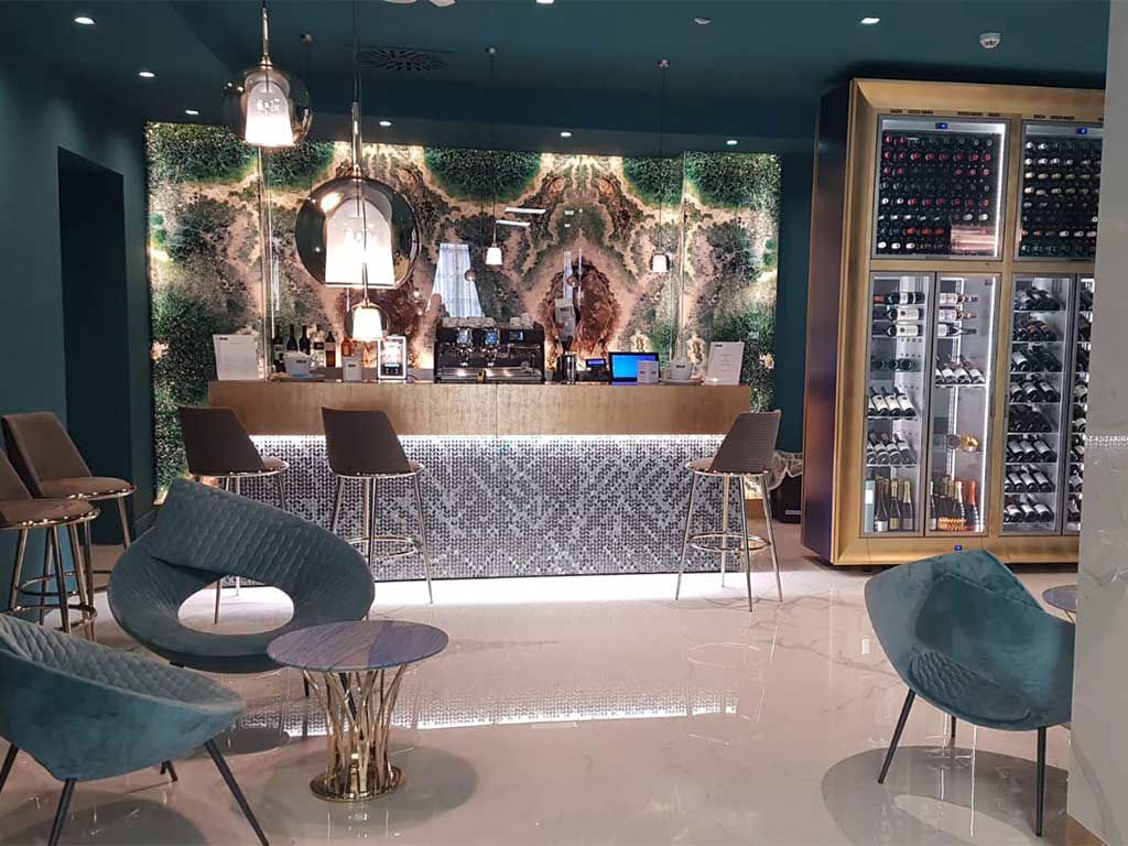 Moderne Bar mit elegantem Interieur, grünem Pflanzenmuster und einer großen Weinlagervitrine.