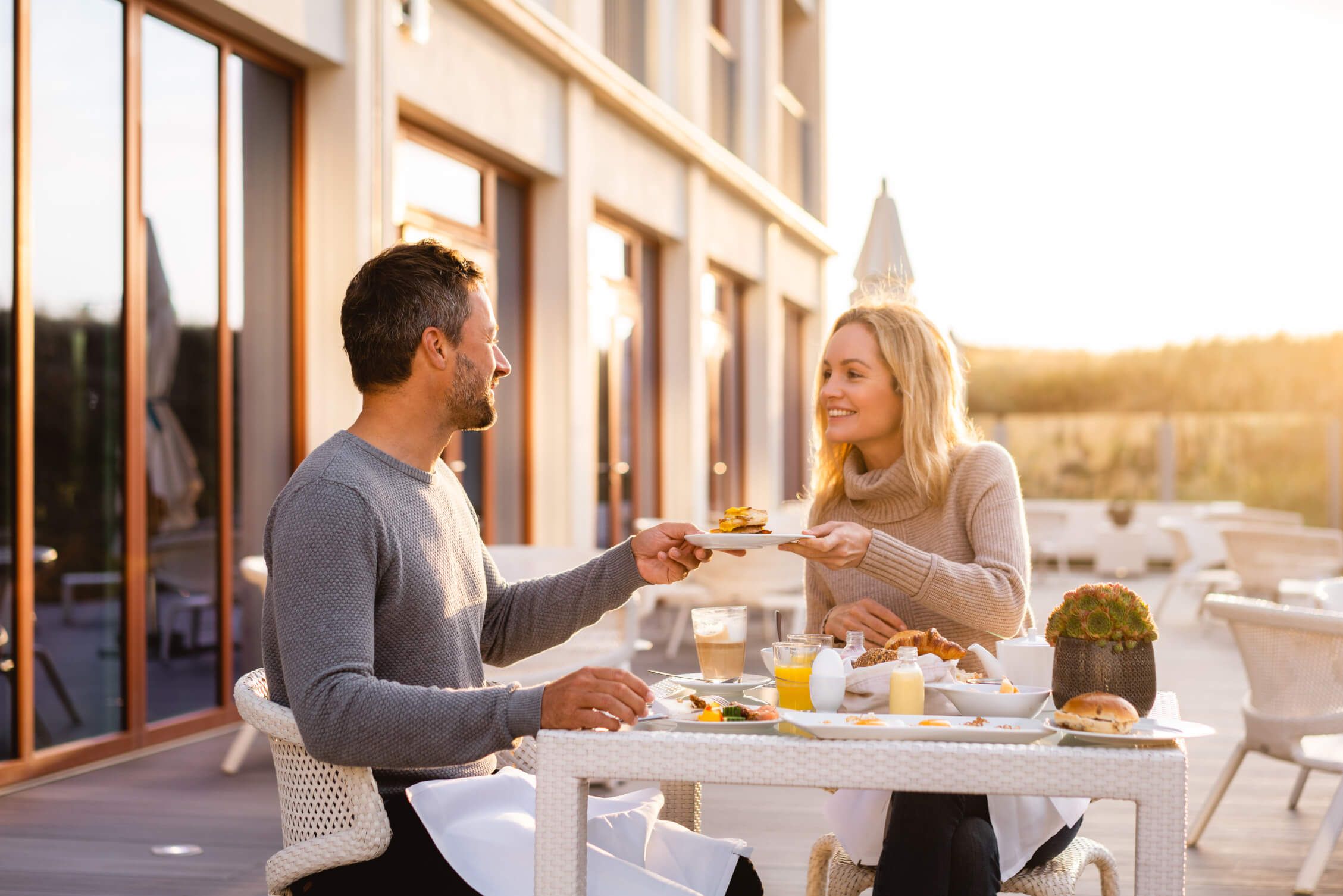 Ein Paar genießt ein Frühstück im Freien, lächelt sich an und teilt eine Mahlzeit bei Sonnenaufgang.