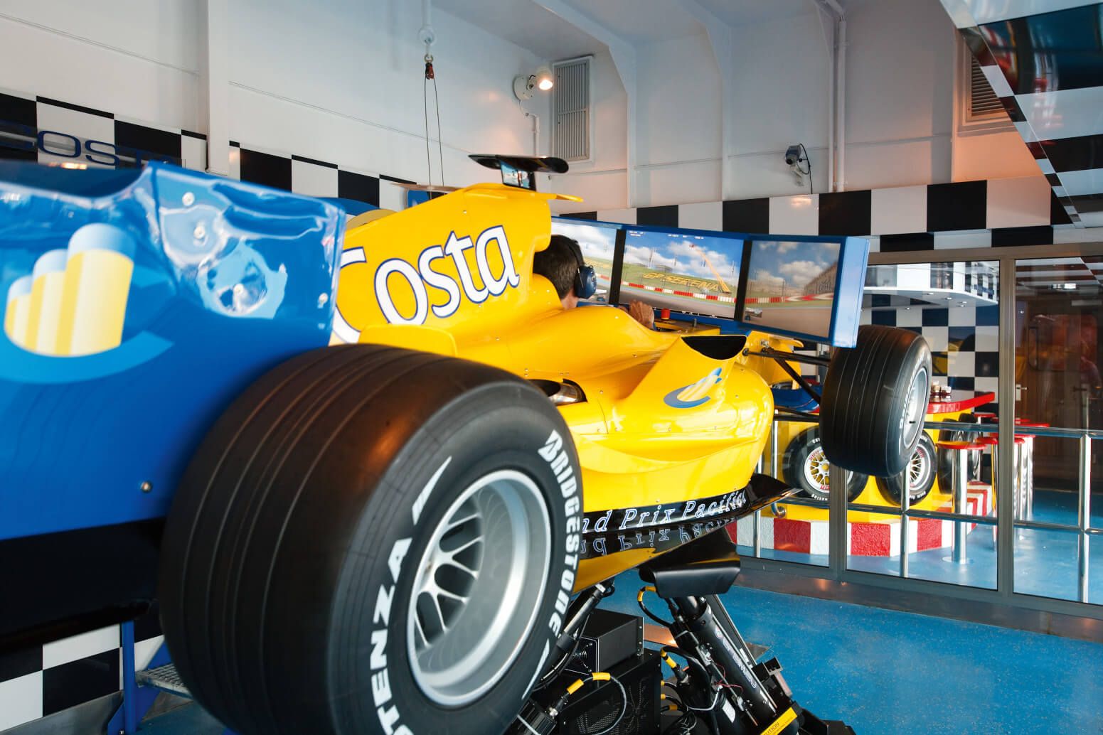 Ein gelbes Formel-1-Rennspiel mit mehreren Bildschirmen in einem modernen Racing-Simulator.