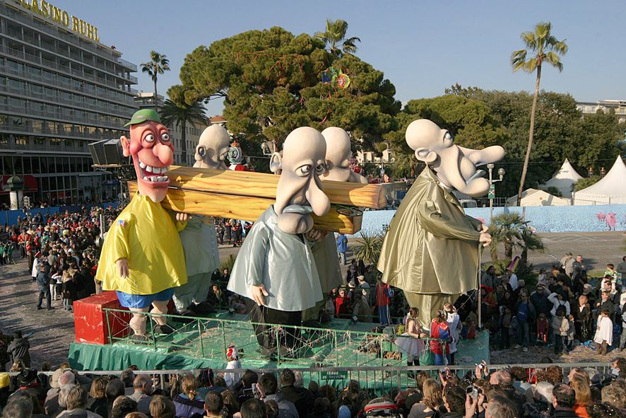 Eine bunte Karnevalsparade mit großen Puppen und jubelnden Menschenmengen im Hintergrund.