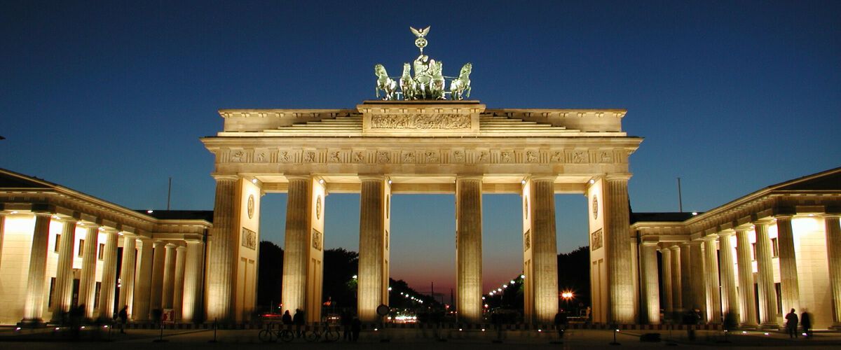 Das Brandenburger Tor bei Nacht, erleuchtet, mit dem berühmten Quadriga auf dem Dach. Ein Wahrzeichen Berlins.