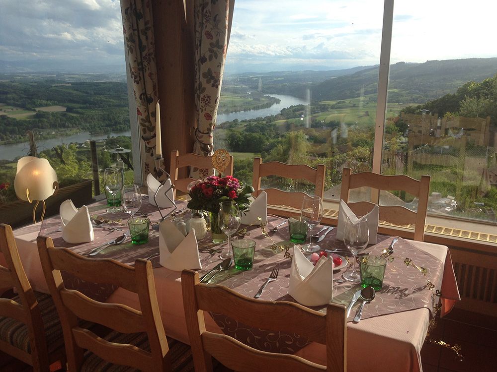 Ein schön gedeckter Tisch mit Blick auf eine Landschaft mit Fluss und Bergen, perfekt für ein besonderes Essen.