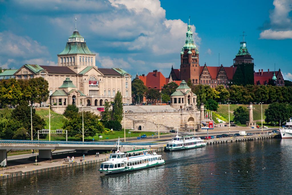 Eine hübsche Stadtansicht mit historischen Gebäuden und Booten auf dem Wasser unter einem blauen Himmel.