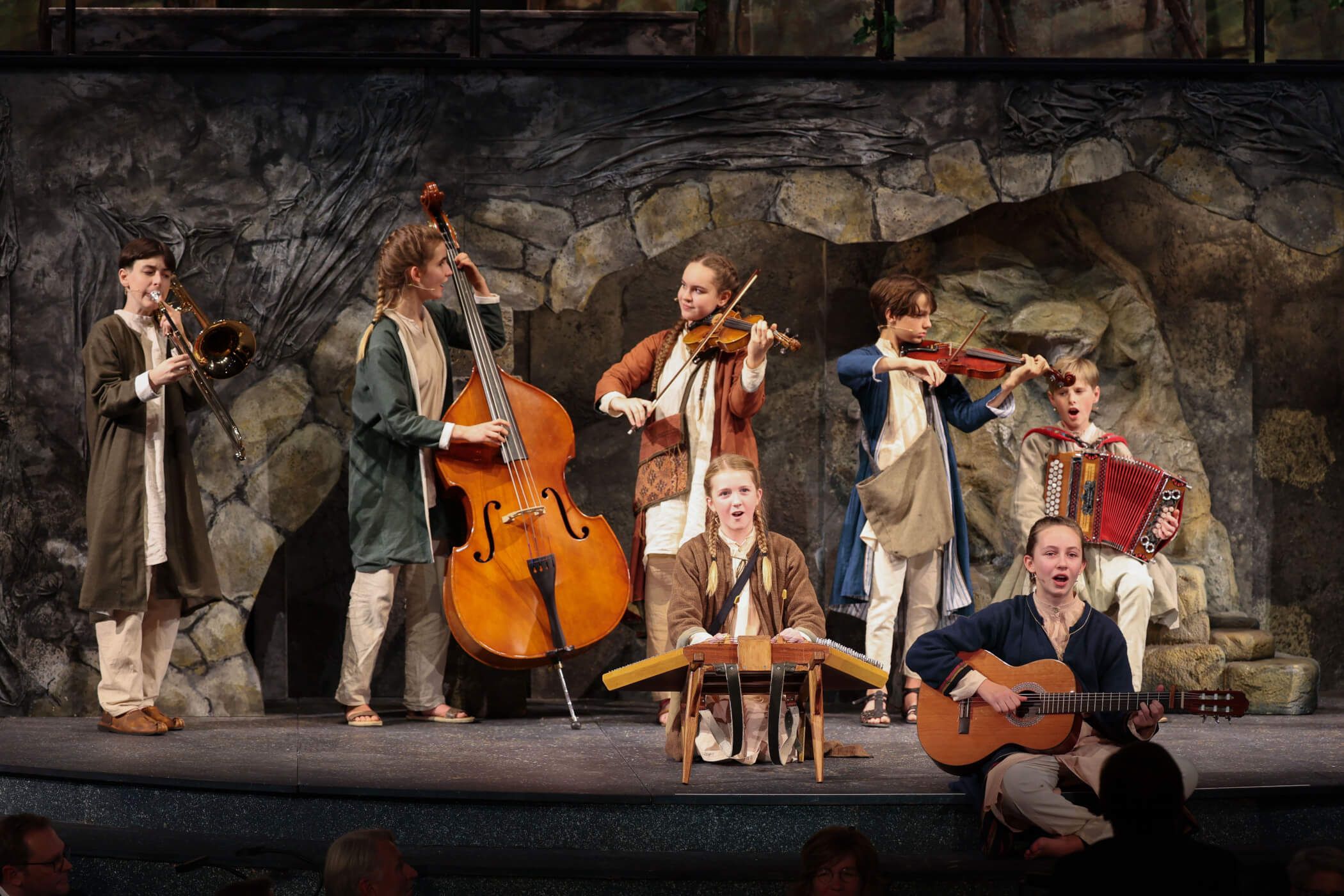 Acht Musiker auf einer Bühne spielen verschiedene Instrumente in einem lebhaften Auftritt.