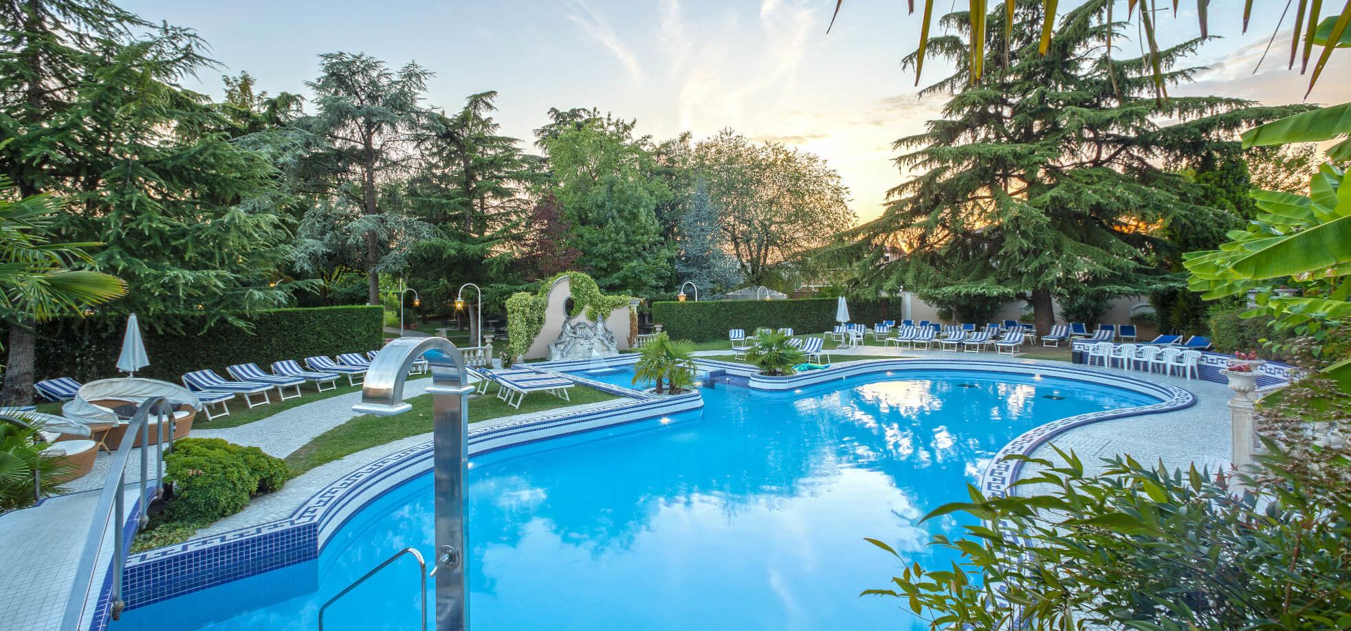 Ein ruhiger Poolbereich umgeben von Bäumen und Liegen, ideal für Entspannung und Erholung.