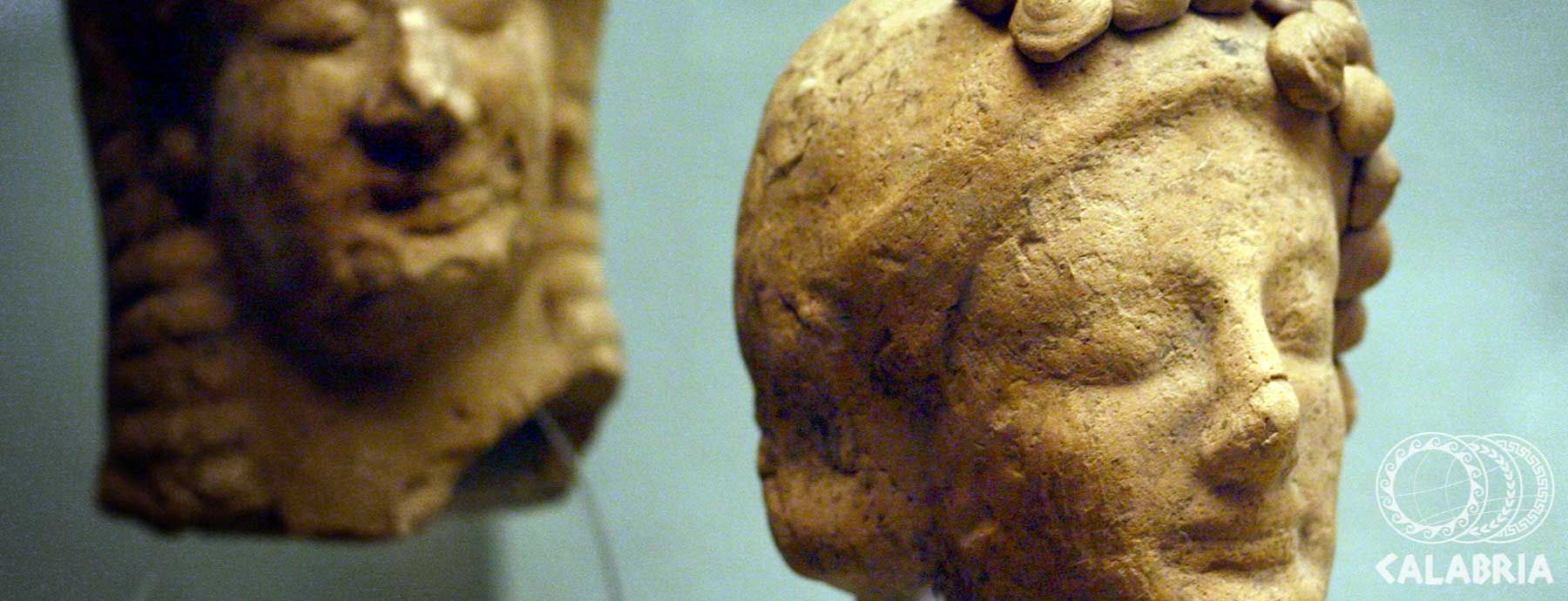 Zwei antike Köpfe aus Ton, einer mit geschlossenen Augen, der andere zur Seite geneigt. Historische Artefakte.