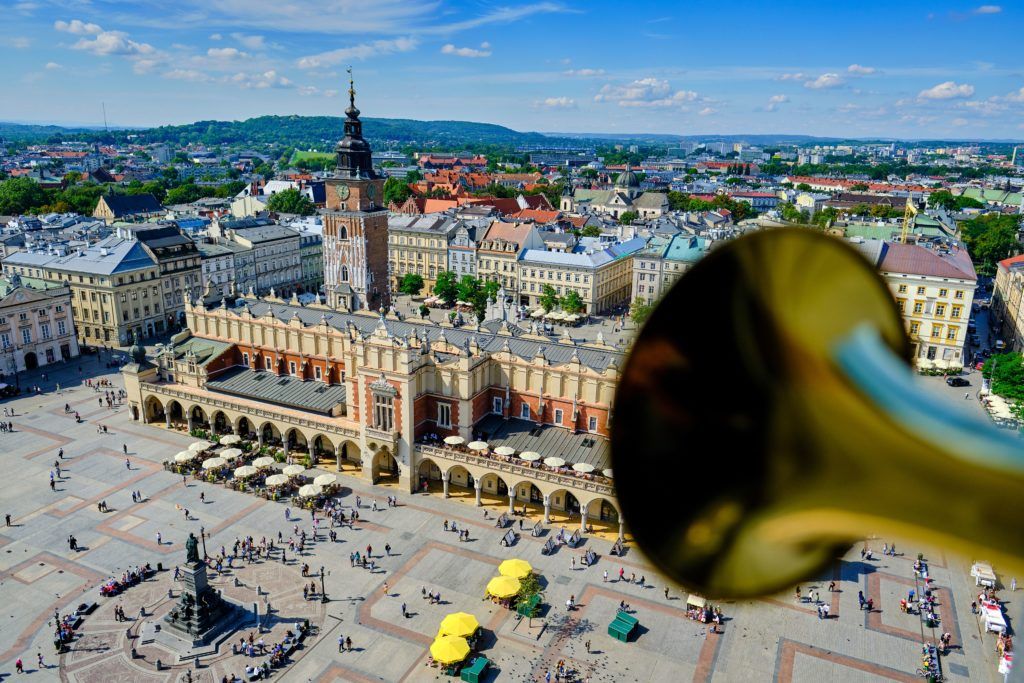 Blick über den Marktplatz mit dem historischen Rathaus und Menschenmengen, im Vordergrund ein Trompetenmundstück.