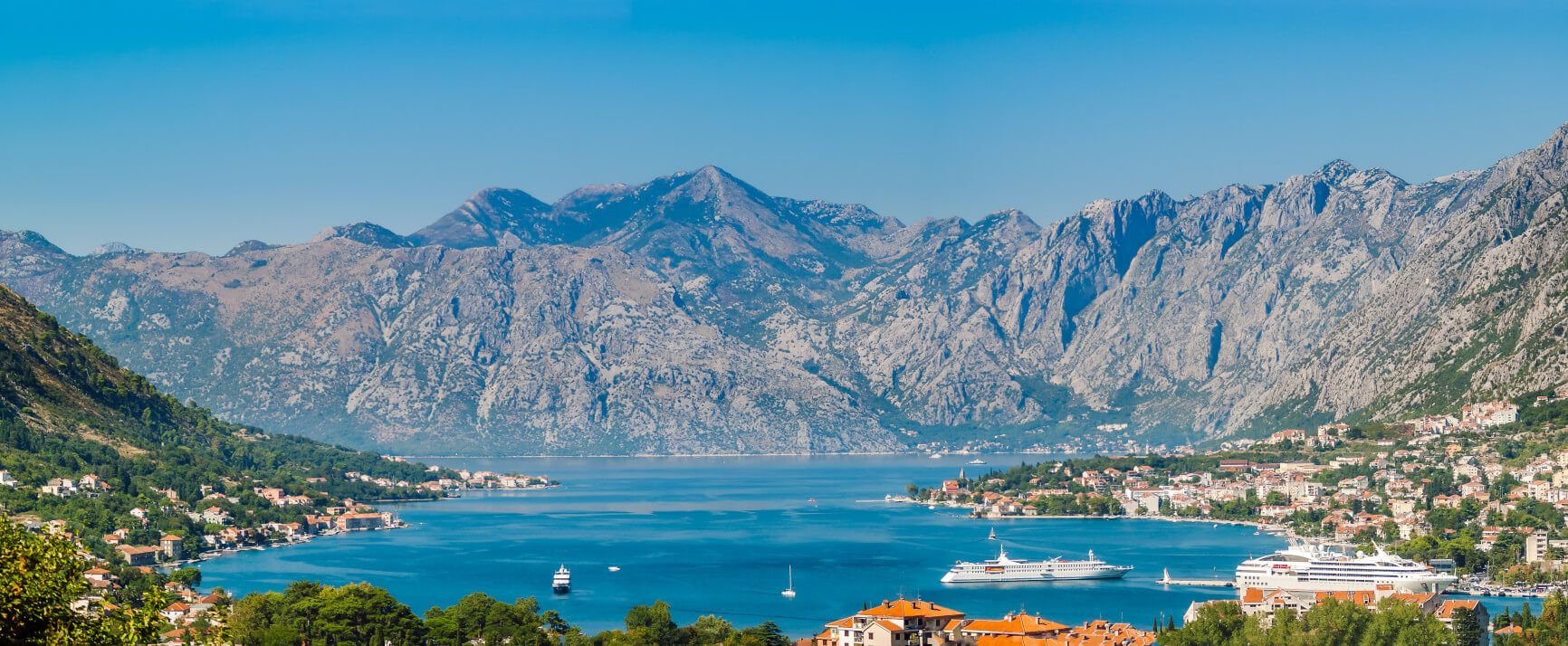 Ein malerischer Blick auf die Bucht von Kotor, umgeben von beeindruckenden Bergen und schönen Häusern.