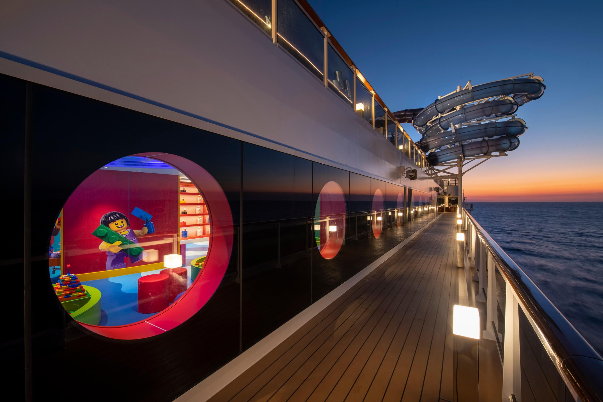 Ein Blick auf ein Kreuzfahrtschiff mit einer bunten Spielstation für Kinder und traumhaftem Sonnenuntergang.