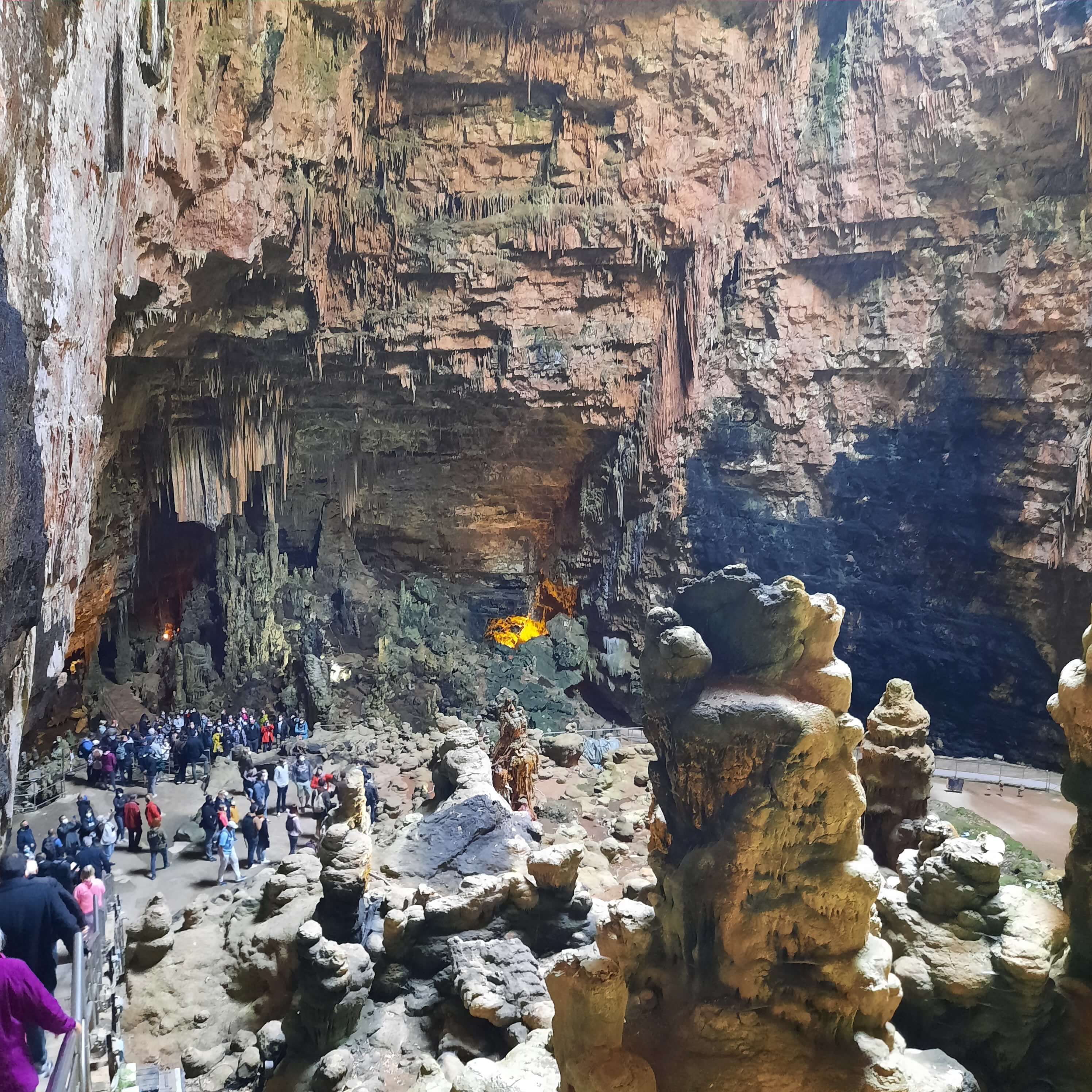 Große Höhle mit beeindruckenden Stalaktiten und vielen Besuchern, umgeben von einzigartigen Felsformationen.