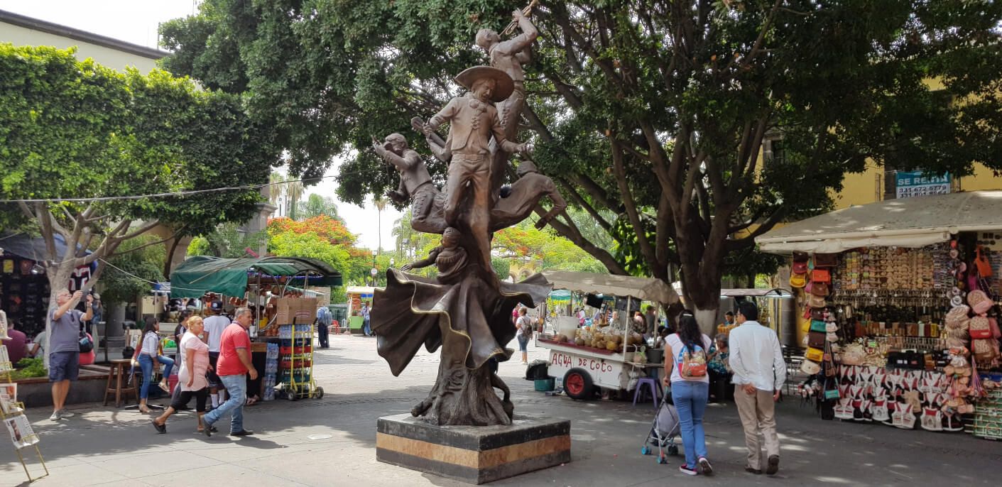 Eine lebendige Marktszene mit einer beeindruckenden Statue im Zentrum und bunten Verkaufsständen.