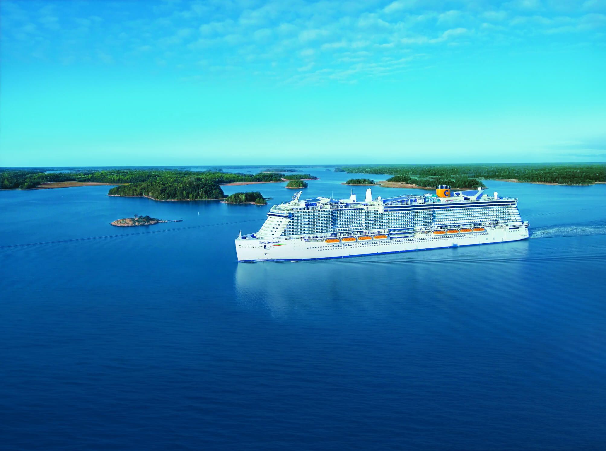 Ein großes Kreuzfahrtschiff fährt durch ruhiges Wasser, umgeben von grünen Inseln und blauem Himmel.