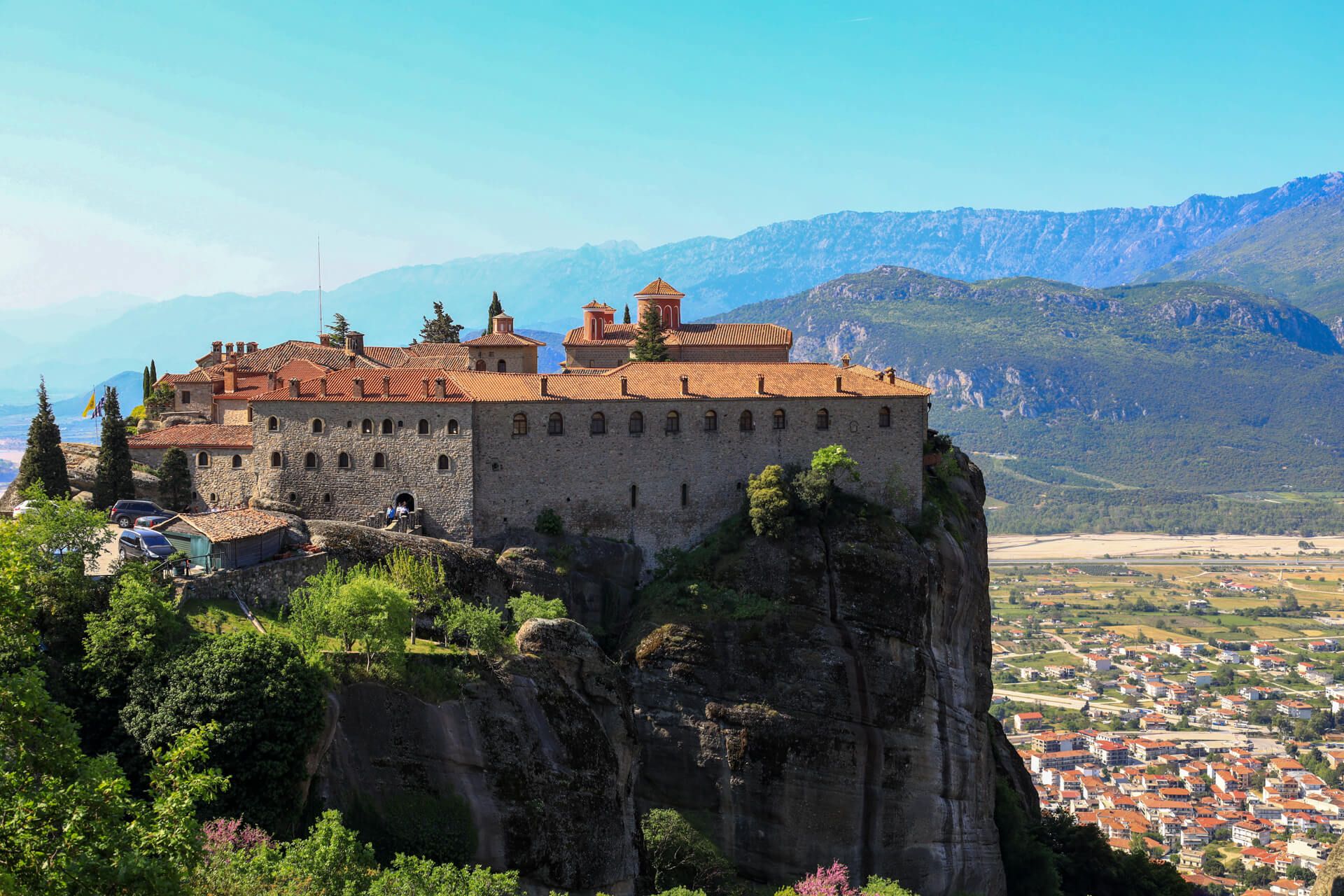 Eine beeindruckende Klosteranlage auf einem Felsen, umgeben von Bergen und einer malerischen Landschaft.