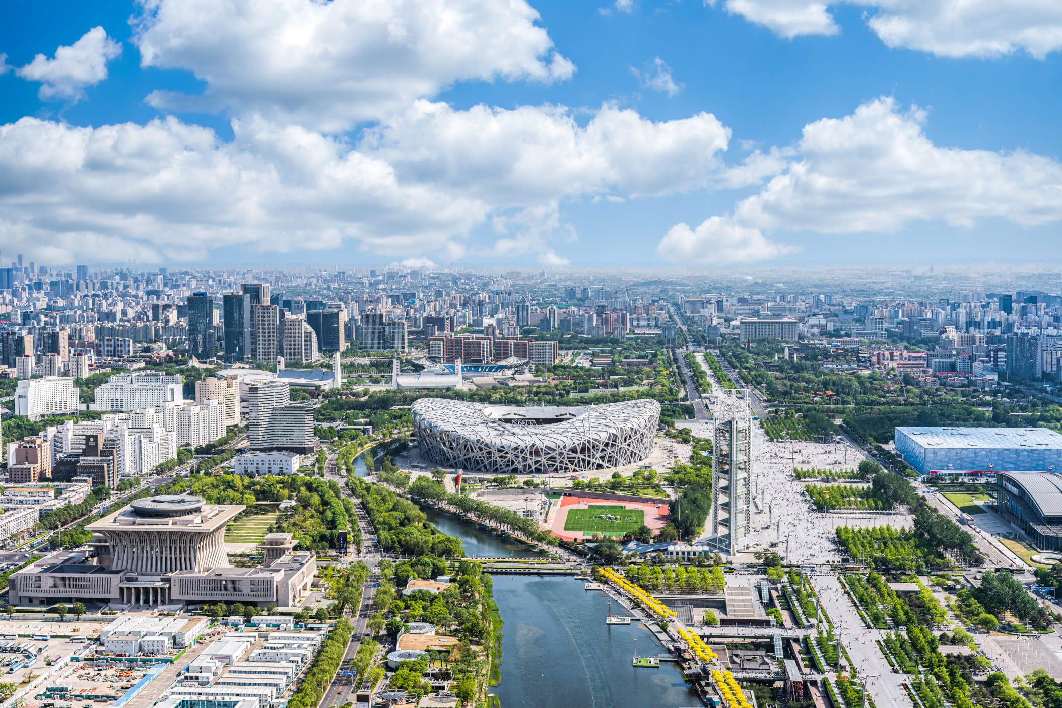 Blick auf die moderne Skyline von Peking mit dem Vogelnest-Stadion und weitläufigen Grünflächen.
