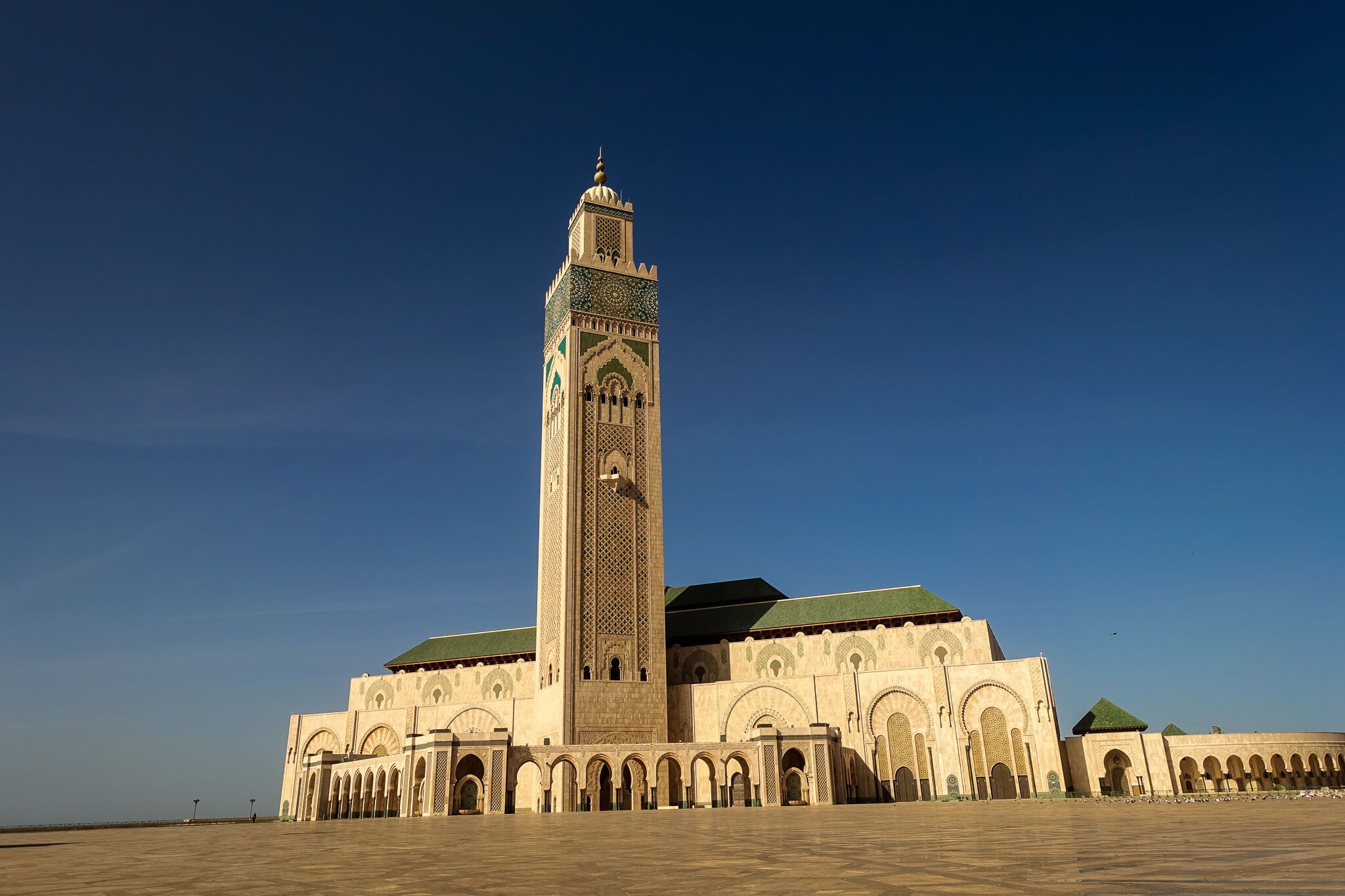 Eine beeindruckende Moschee mit hohen Türmen und kunstvollen Verzierungen unter klarblauem Himmel.