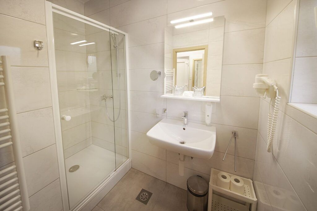 Modernes Badezimmer mit Dusche, Waschbecken, Spiegel und Handtuchheizung in neutralen Farben.