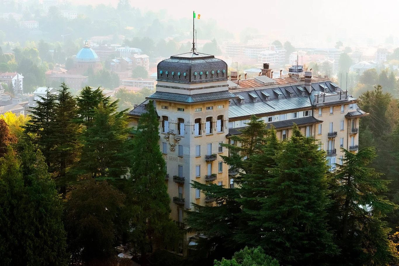 Ein prächtiges Gebäude umgeben von Bäumen, mit einer Fahne auf dem Dach und einer malerischen Aussicht.