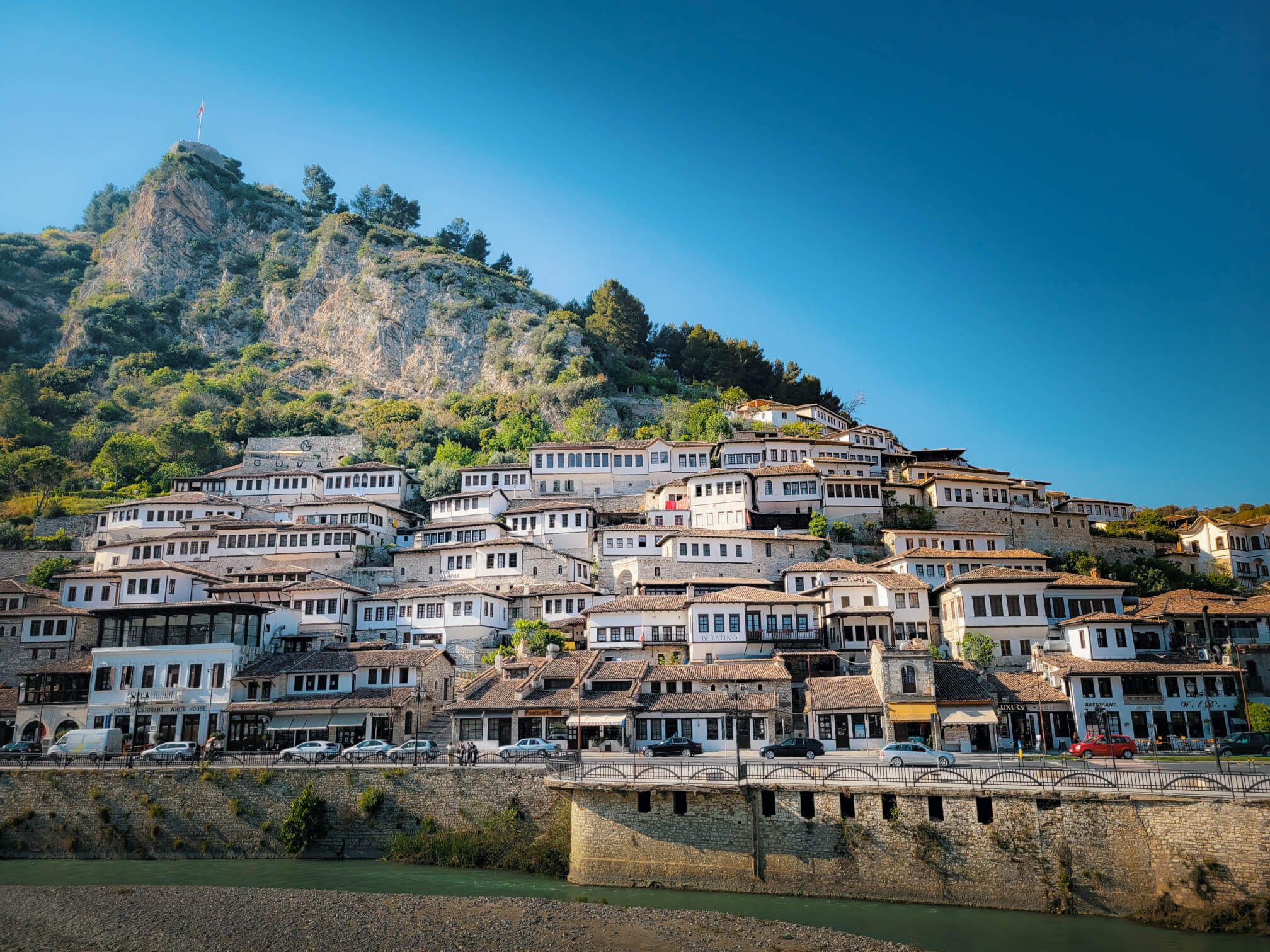 Eine malerische Stadt mit traditionellen Häusern am Berghang und klarem Himmel, umgeben von grüner Natur.