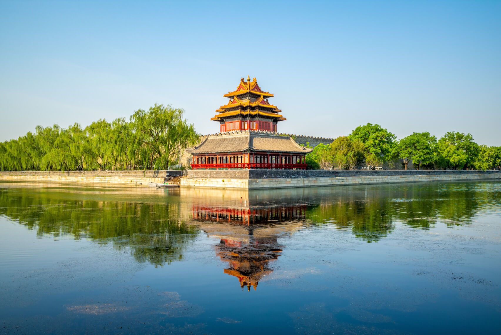 Eine historische chinesische Architektur spiegelt sich im ruhigen Wasser unter blauem Himmel.