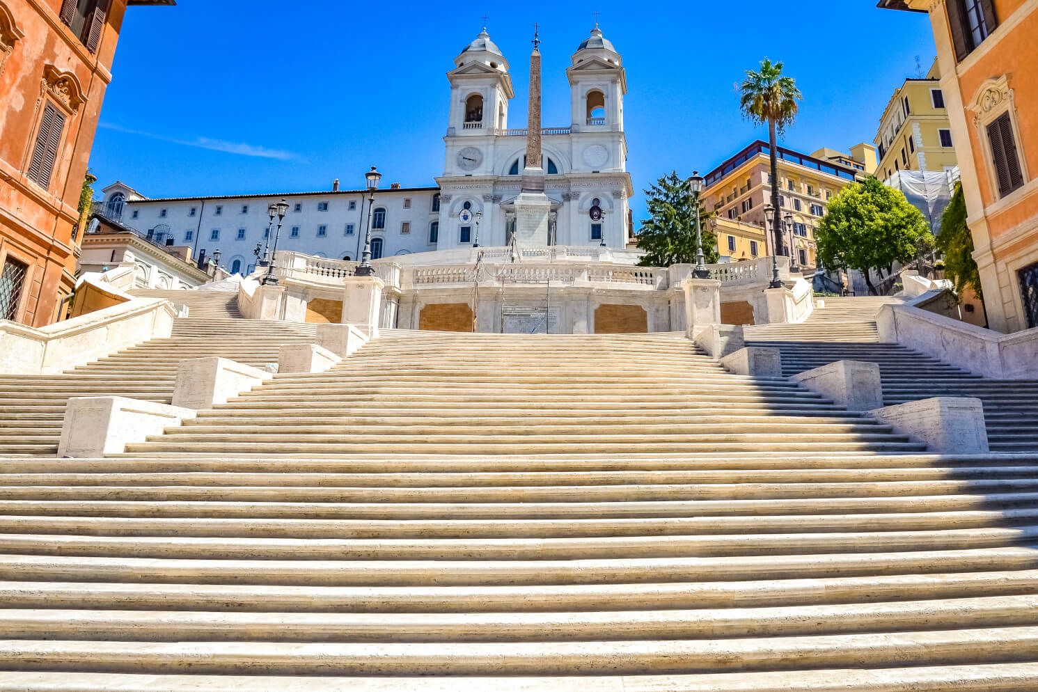Die Treppe zur Kirche Trinità dei Monti mit strahlend blauem Himmel und lebendiger Architektur im Hintergrund.