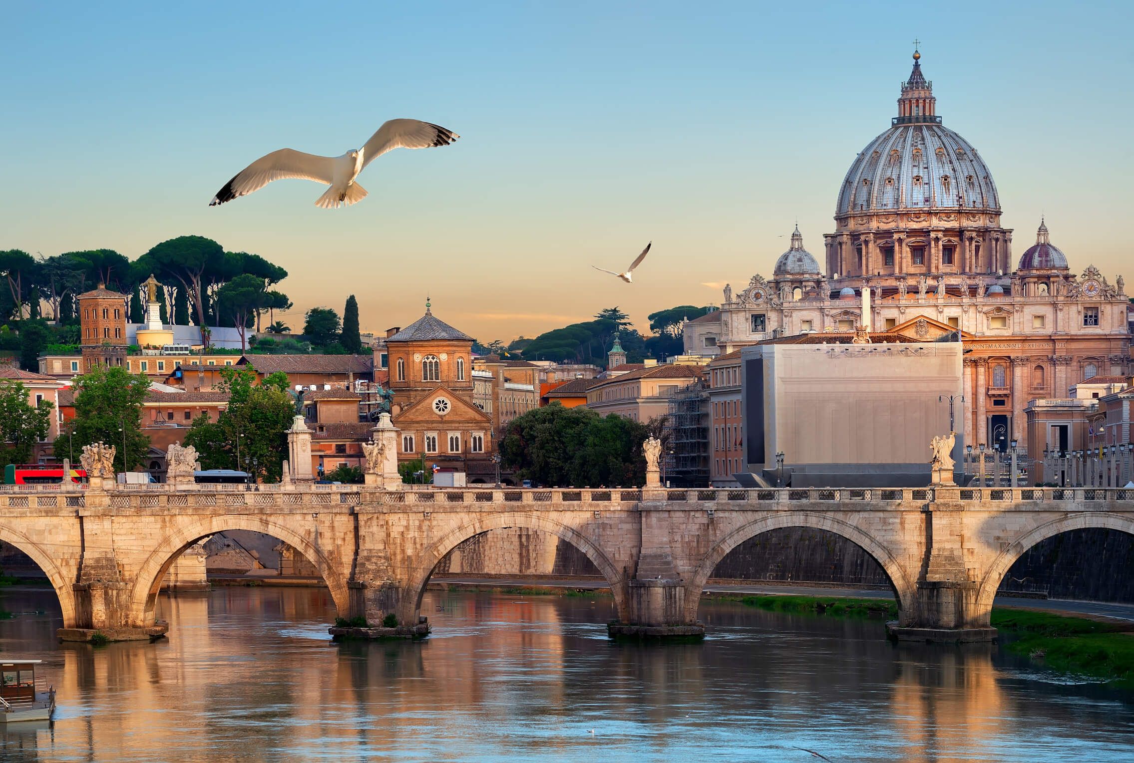 Schöne Aussicht auf den Tiber, Brücke und Petersdom, umgeben von Bäumen und Vogelgezwitscher im Morgenlicht.