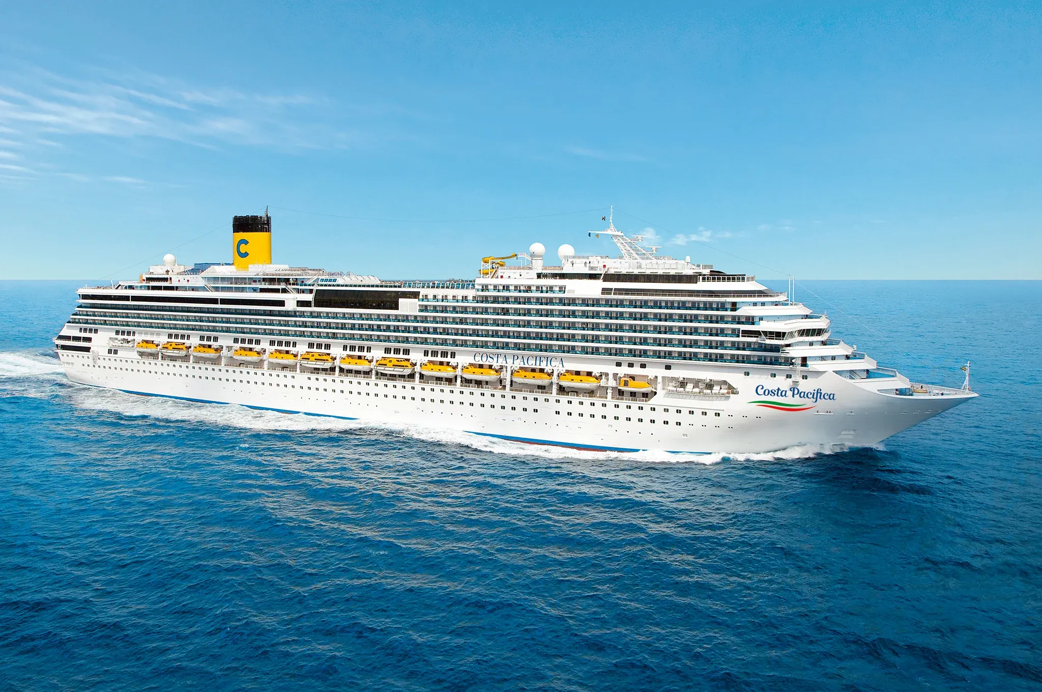 Ein großes Kreuzfahrtschiff, die Costa Pacifica, gleitet durch das türkisfarbene Wasser unter klarem Himmel.