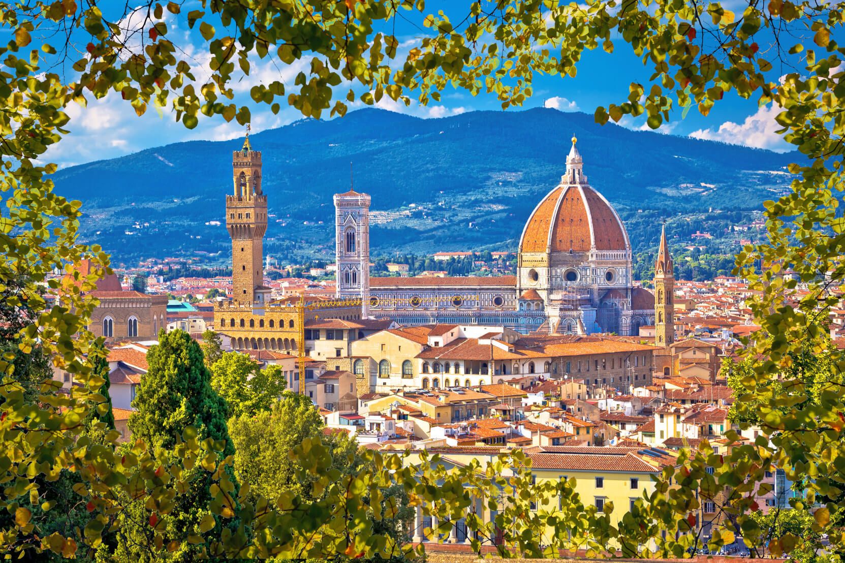 Blick auf Florenz mit der beeindruckenden Kathedrale und dem historischen Palazzo Vecchio, umgeben von grüner Natur.