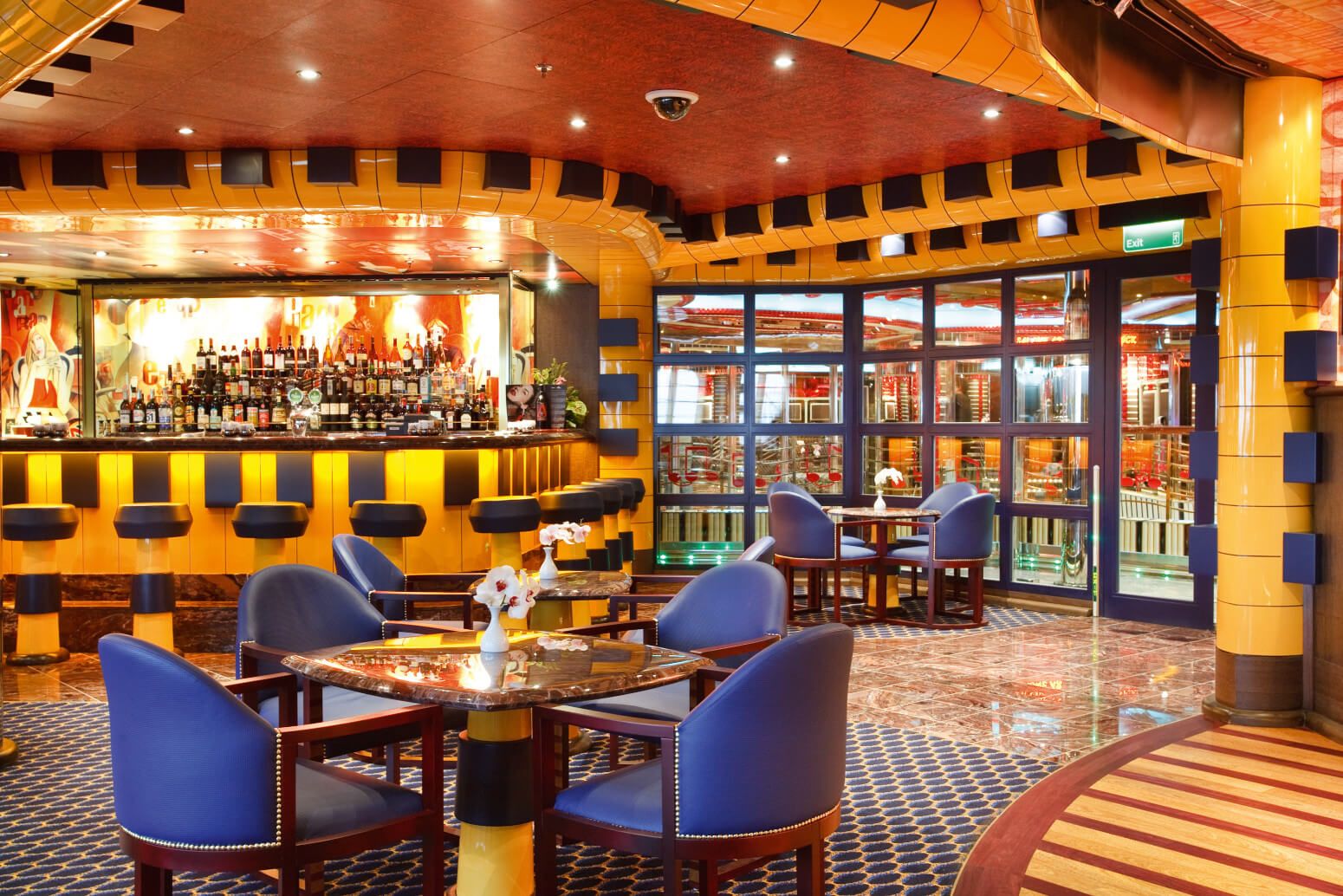 Ein stilvolles Bar-Interior mit runden Tischen, blauen Stühlen und einer beeindruckenden Getränketheke.