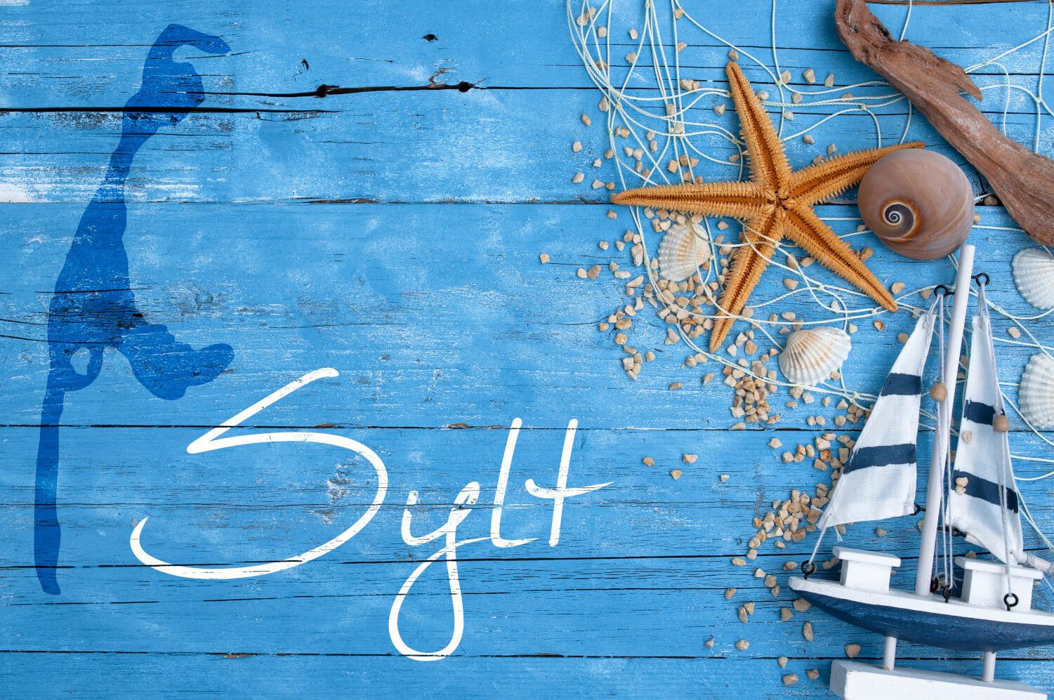 Blaue Holzoberfläche mit Sternen, Muscheln und einem kleinen Segelboot. „Sylt“ in geschwungener Schrift platziert.