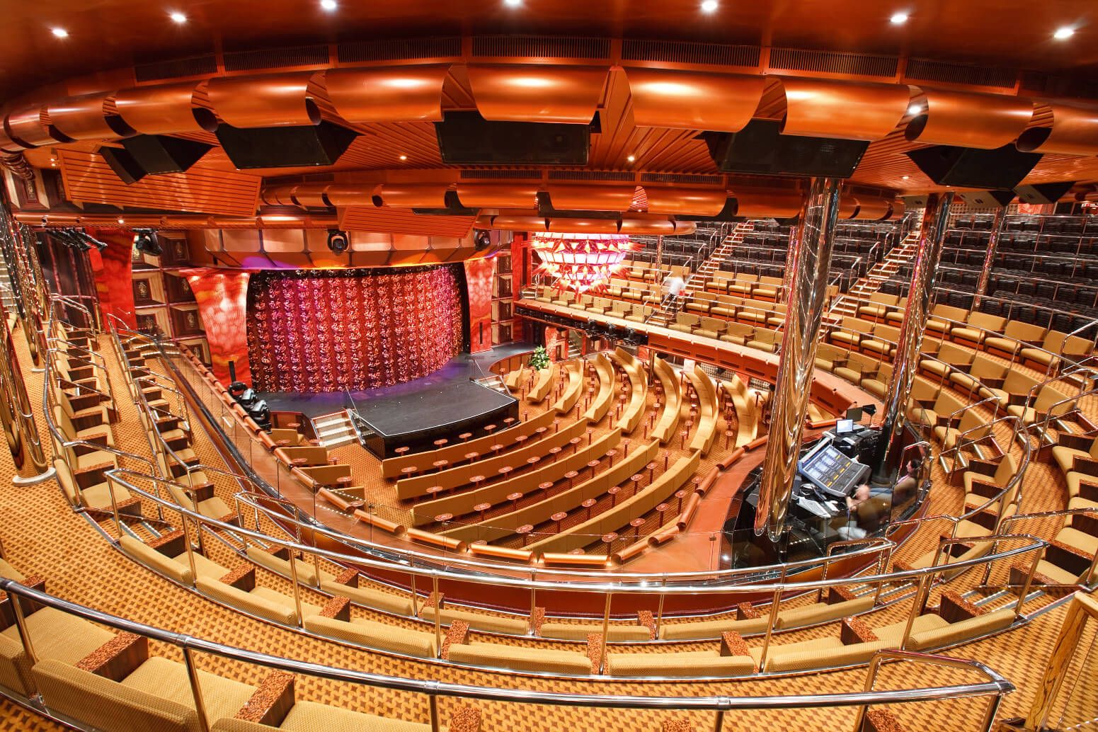 Ein modernes Theater mit vielen Sitzplätzen und einer Bühne wird von warmem Licht beleuchtet.