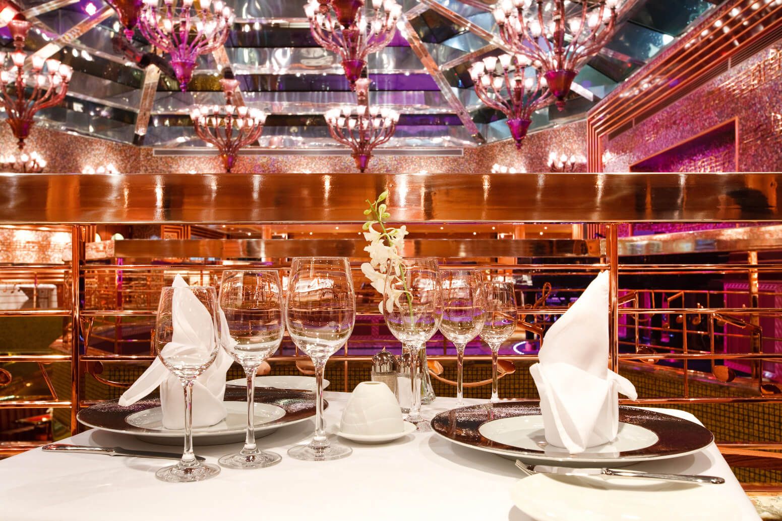 Elegant gedeckter Tisch in einem stilvollen Restaurant mit funkelnden Kronleuchtern und schöner Dekoration.