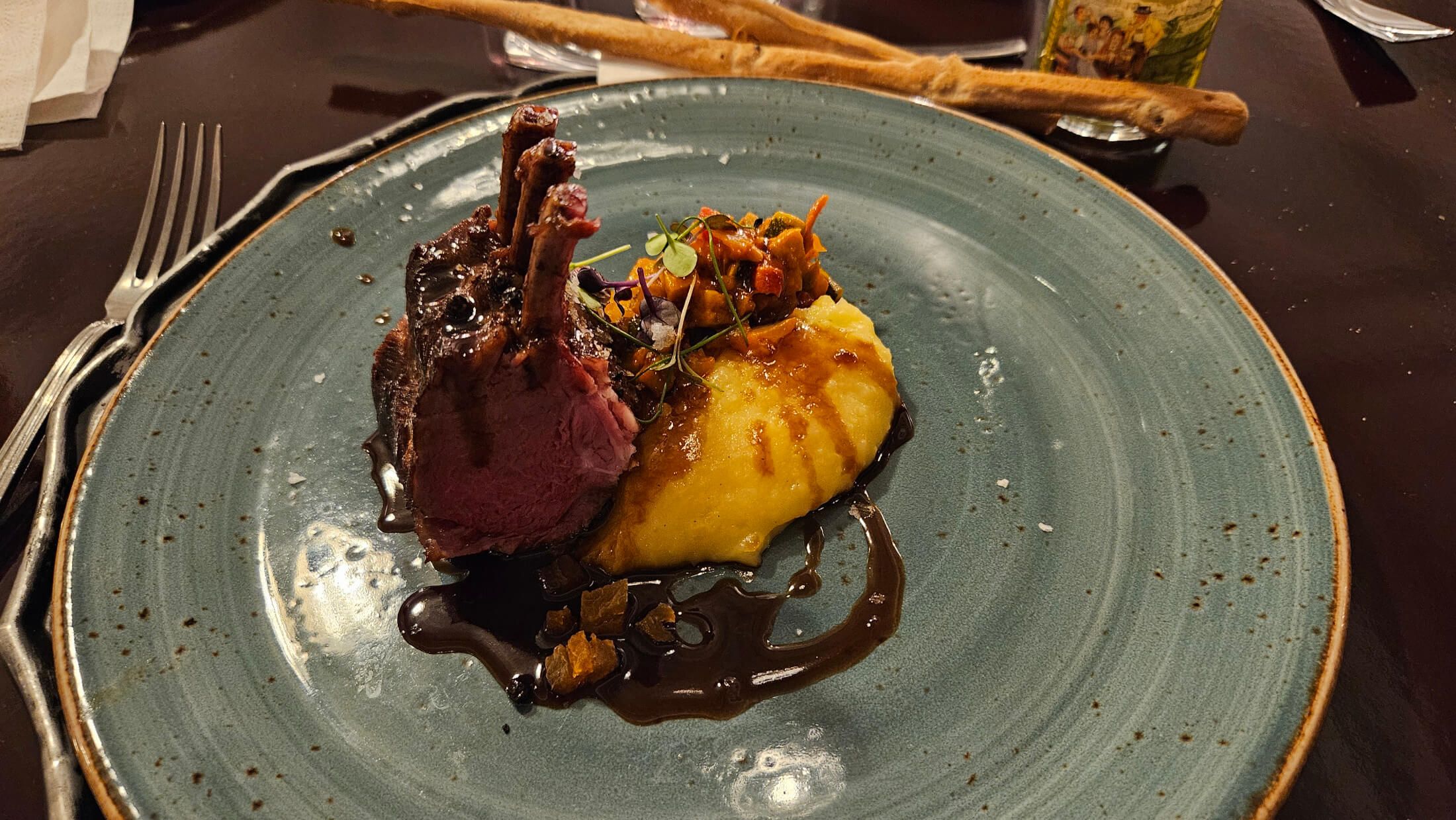 Ein Teller mit zartem Fleisch, Püree, Gemüse und einer dunklen Sauce, elegant angerichtet.