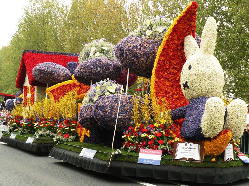 Ein festlich dekorierter Wagen mit Blumen, einem Haus und einem großen Kaninchen aus Pflanzen.