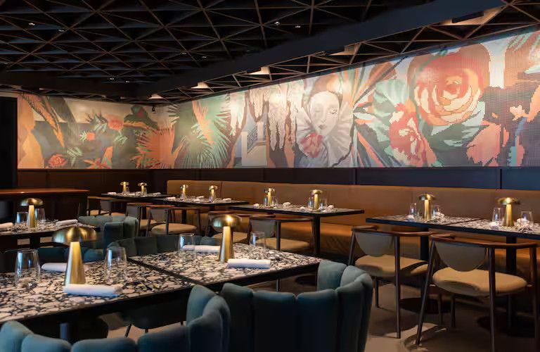 Elegante Restaurant mit modernen Tischen, stilvollen Stühlen und einer farbenfrohen Wandgestaltung.